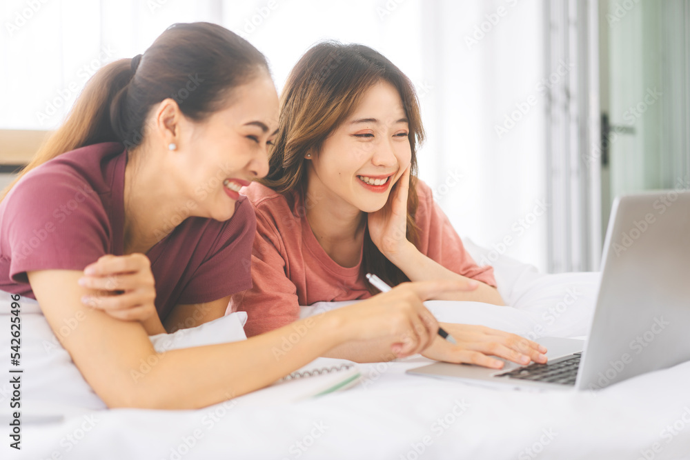 Two young adult woman living together with relationship laying at bedroom talking about work in the morning Two young adult woman living together with relationship laying at bedroom talking about work in the morning