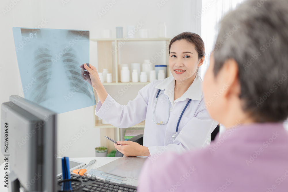 Fototapeta premium Asian doctor looking patient film, she talk with patient about disease, broken bone treatment, tuberculosis screening