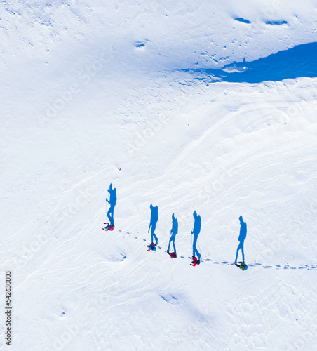 Walking shadows - hikers seen from above with their shadows like waking in the snow