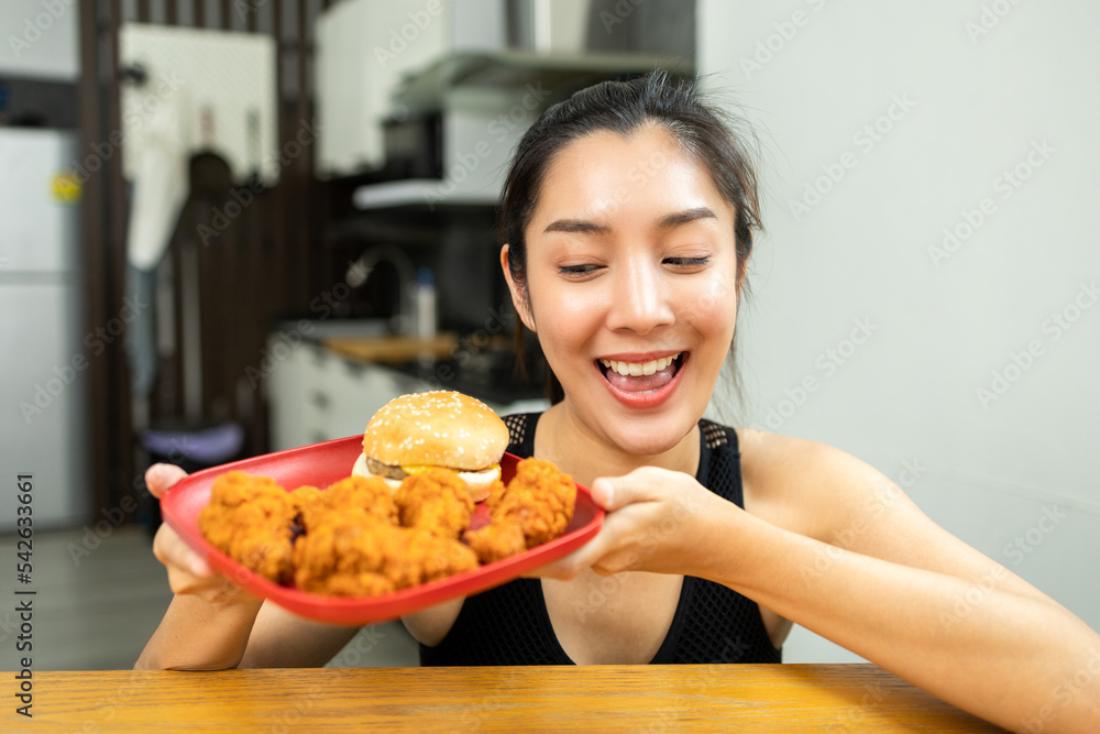 Beautiful female in sportswear fried chicken junk food high calorie food and health risks. Hungry young woman eating Fried Chicken Beautiful female in sportswear fried chicken junk food high calorie food and health risks. Hungry young woman eating Fried Chicken