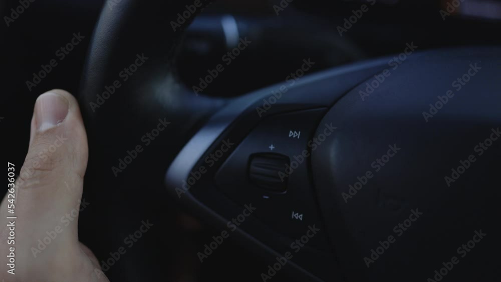 Close-up view of steering wheel of car control music. The hand turns the volume of the radio in the car. Close up of radio volume. Music in the car. Modern music technology Close-up view of steering wheel of car control music. The hand turns the volume of the radio in the car. Close up of radio volume. Music in the car. Modern music technology