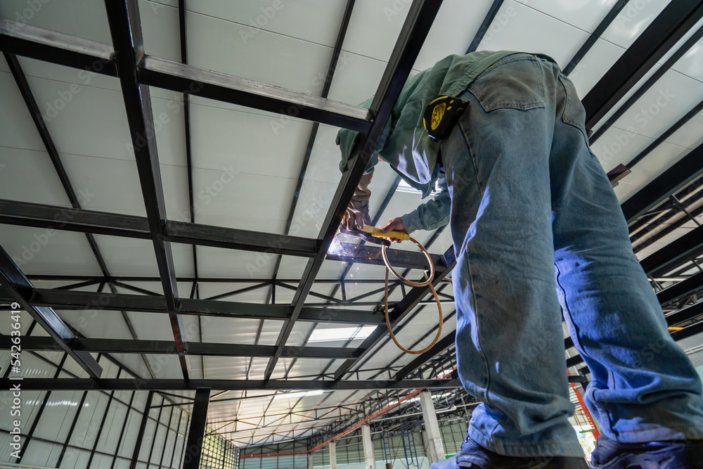 Asian construction workers weld steel in an industrial construction site.