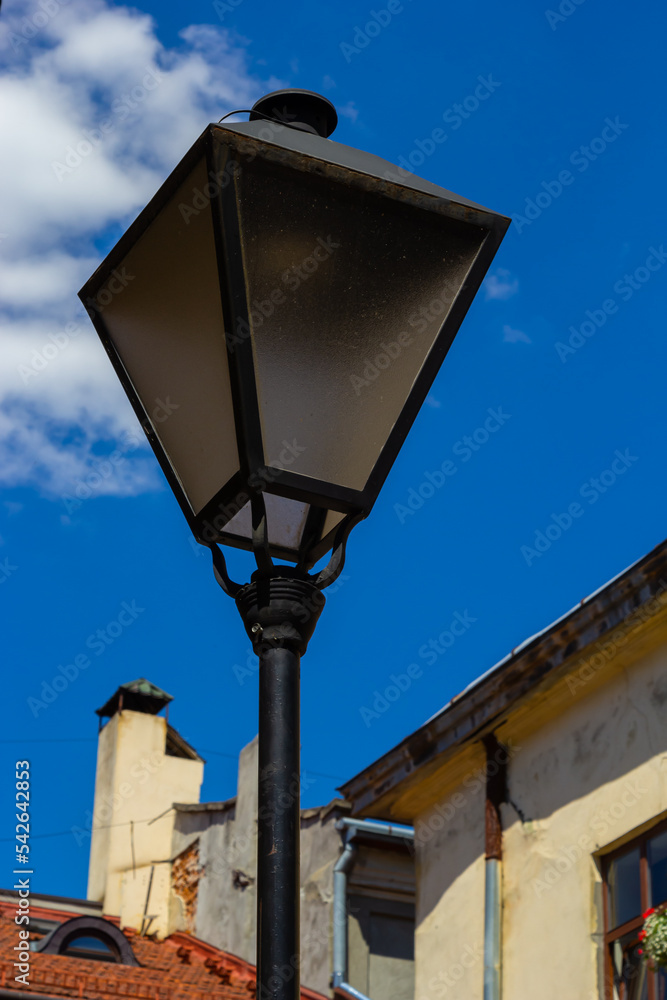 Old-fashioned street wall lamp made of black metal. Gray facade of an old house. Lviv, Ukraine Old-fashioned street wall lamp made of black metal. Gray facade of an old house. Lviv, Ukraine