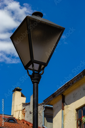 Old-fashioned street wall lamp made of black metal. Gray facade of an old house. Lviv, Ukraine