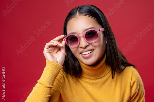 Smiling happy girl touching the rim of her sunglasses