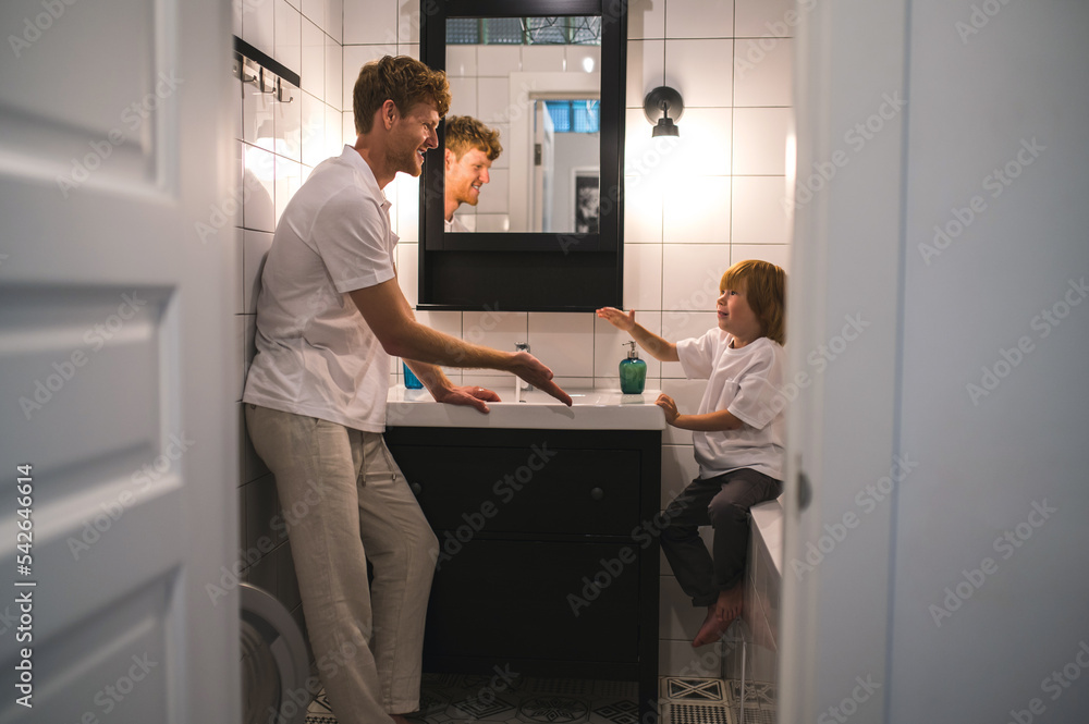 Cute little boy and his dad washing hands in the bathroom