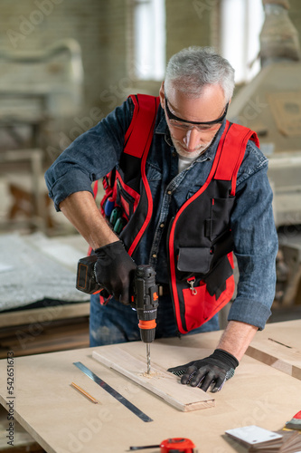 Craft person drlling wood in the workshop photo