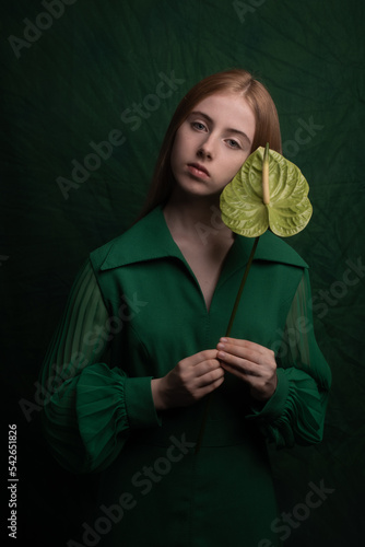 classic painterly studio portrait of a woman in green dress holding leaf
