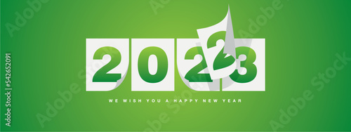 Happy New Year 2023 greeting card design template on lucky green background. New Year 2023 start concept. Calendar pages turn in the wind and the new year begins