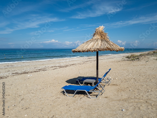 A deserted beach with sun bed and natural umbrella with a view of the horizon and deep blue sea. photo