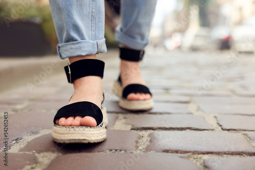 Woman in stylish sandals walking on city street, closeup. Space for text