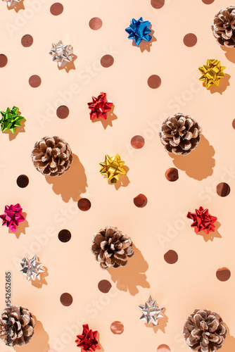 Creative layout made of pine cones and sparkle bow ties on pastel background. Minimal Christmas decorative concept. Winter or new year holiday coposition.