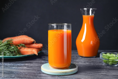 Tasty refreshing carrot juice on black marble table