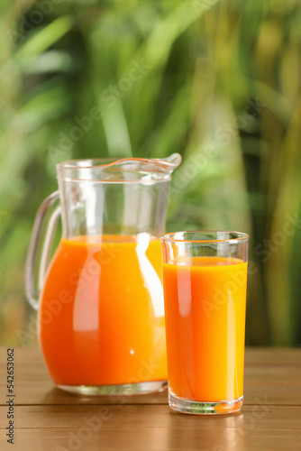 Tasty refreshing carrot juice on wooden table outdoors