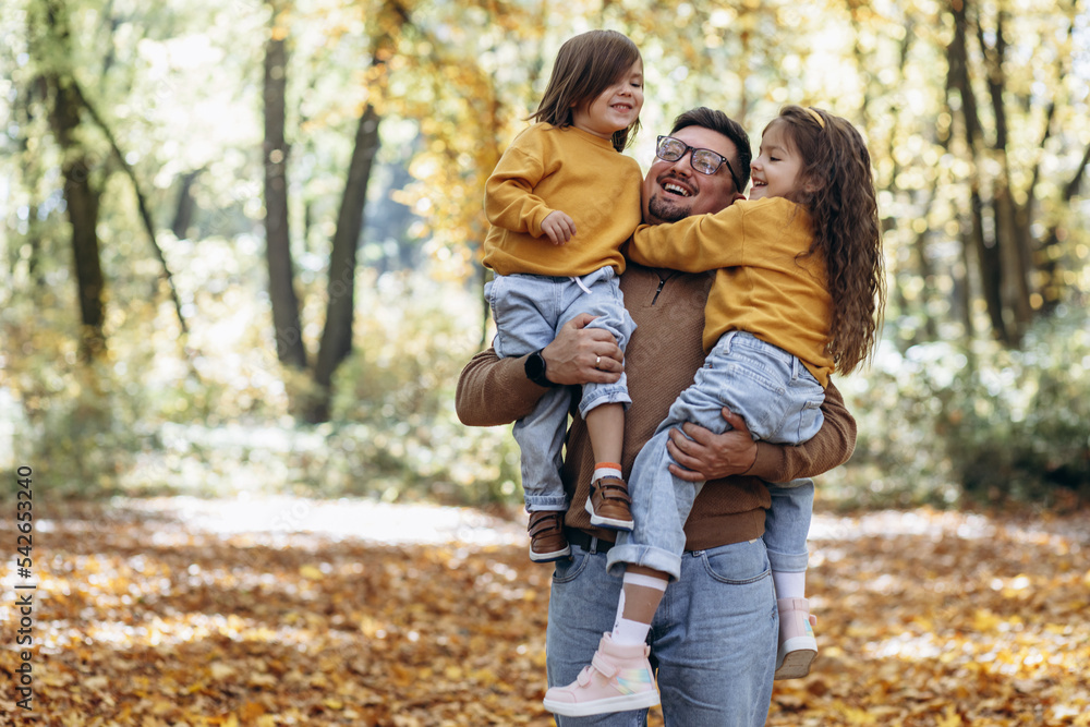 Father with daughters having fun in autumnal park Father with daughters having fun in autumnal park