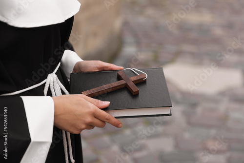 Fotografie Young nun with Christian cross and Bible outdoors, closeup