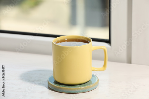 Yellow cup of tea on wooden window sill