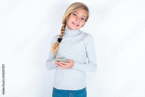 beautiful caucasian teen girl wearing gray turtleneck sweater over white wall Mock up copy space. Using mobile phone  typing sms message