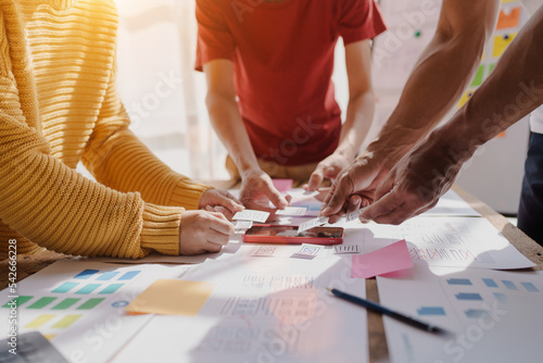 A UX design team is a confluence of user research, UX, UI design with layout paper on desk.