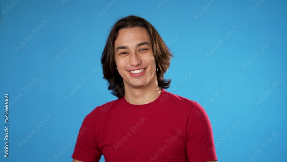 Portrait of happy smiling Hispanic gender fluid young man 20s smiling and giving call me gesture with hands isolated on blue background. Portrait of happy smiling Hispanic gender fluid young man 20s smiling and giving call me gesture with hands isolated on blue background.