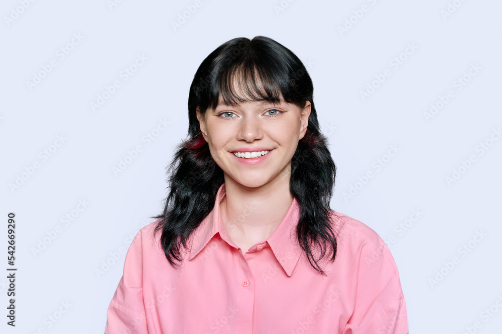 Smiling young female looking at camera on light background Smiling young female looking at camera on light background