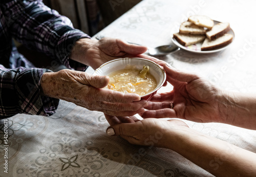 Volunteer gives food to senior at old people house; fragment photo of hands doctor giving soup to retired person