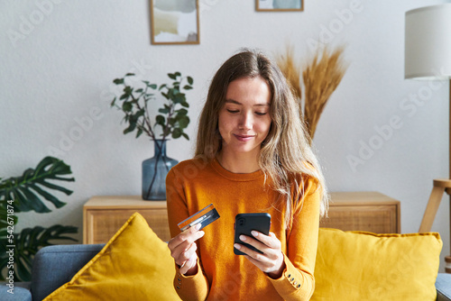Happy woman shopping online with credit card and cell phone at home
