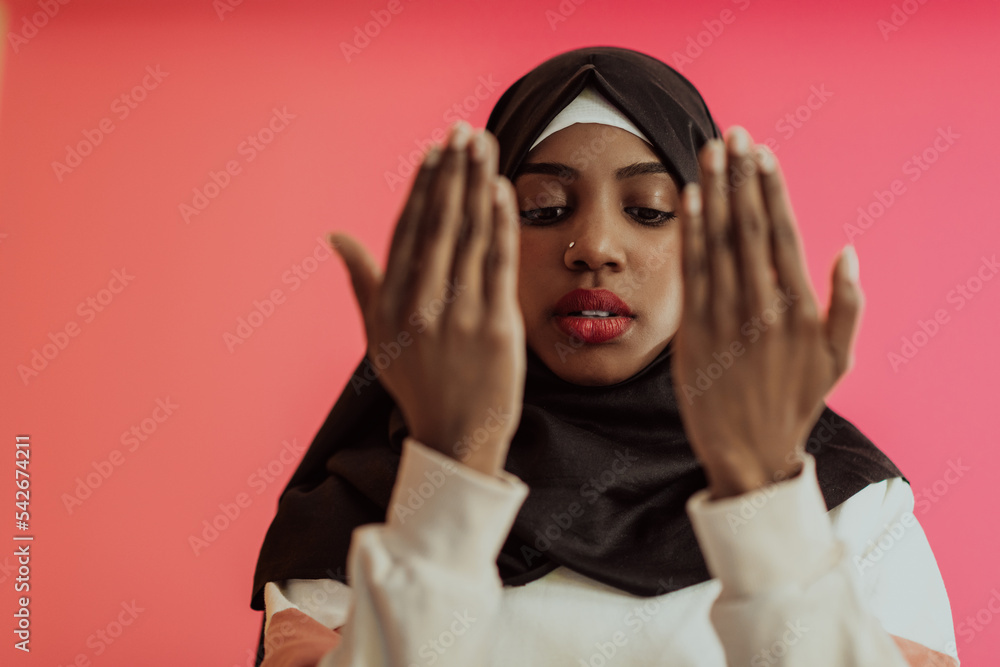 African muslim woman wearing hijab and traditional muslim clothes posing in front of red background African muslim woman wearing hijab and traditional muslim clothes posing in front of red background