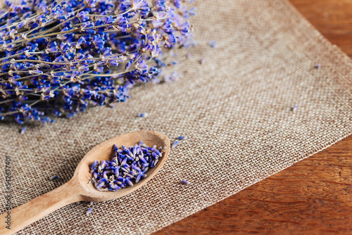 Fotografie Bouquet of lavender flowers and lavender buds in a wooden spoon on a wooden background