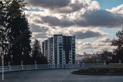 Autumn city park in evening. View from Cascade view point on modern residential building with epic cloudy sky, downtown in Kharkiv, Ukraine