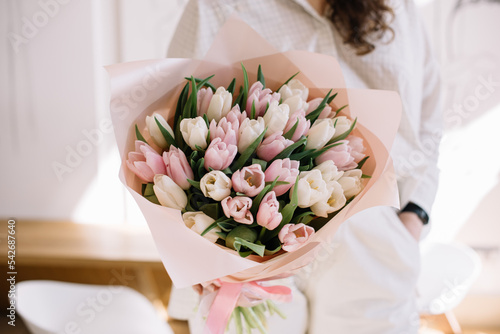 Very nice young woman holding beautiful bouquet of fresh pink and white tulip flowers, cropped photo, bouquet close up