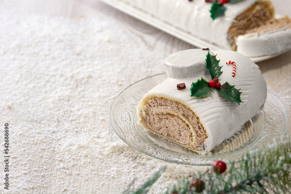 Naklejka premium White chocolate yule log cake with ornaments on wooden table. Copy space