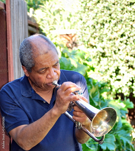 Photography African american jazz musician blowing his flugelhorn outside.