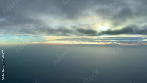 Aerial view from a jet cockpit, pilot point of view, flying bellow some clouds and over Atlantic Ocean near poruguese coast. Sunset. 4k photo