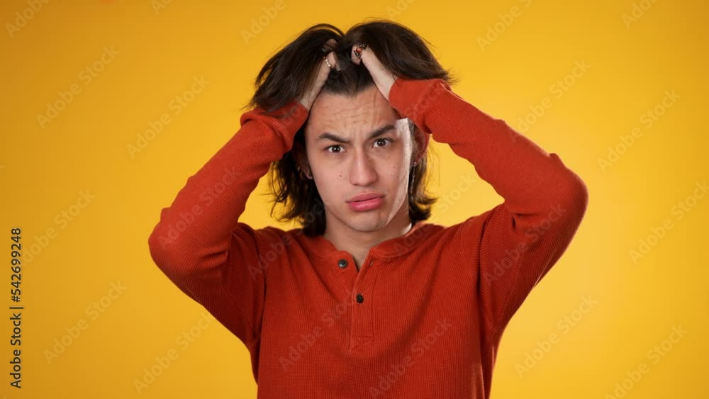 Sick tired headache exhausted displeased gender fluid young man 20s posing isolated on yellow background studio. People lifestyle concept. Put hands on head Sick tired headache exhausted displeased gender fluid young man 20s posing isolated on yellow background studio. People lifestyle concept. Put hands on head