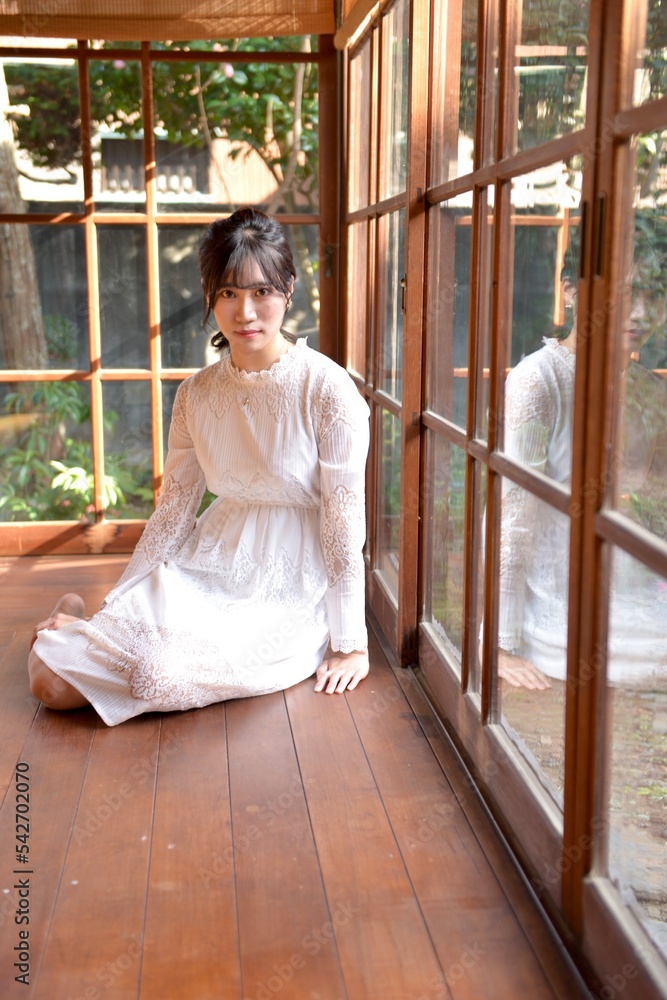 古民家の縁側に座る白いワンピースを着たスリムな若い女性 古民家の縁側に座る白いワンピースを着たスリムな若い女性