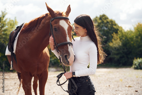 Side view. Young beautiful woman with a horse is outdoors