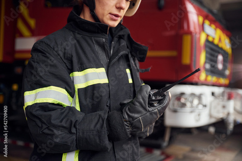 Using radio transmitter. Woman firefighter in uniform is at work in department photo