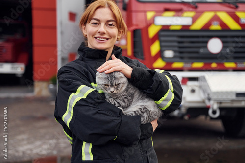 Coneption of animal care. Beautiful scottish fold cat in hands. Woman firefighter in uniform is at work in department photo