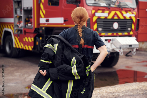 Rear view. Woman firefighter in uniform is at work in department photo