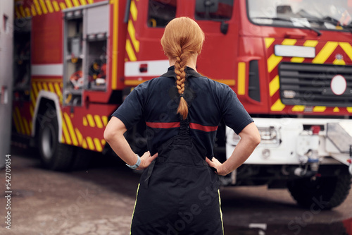 Rear view. Woman firefighter in uniform is at work in department photo