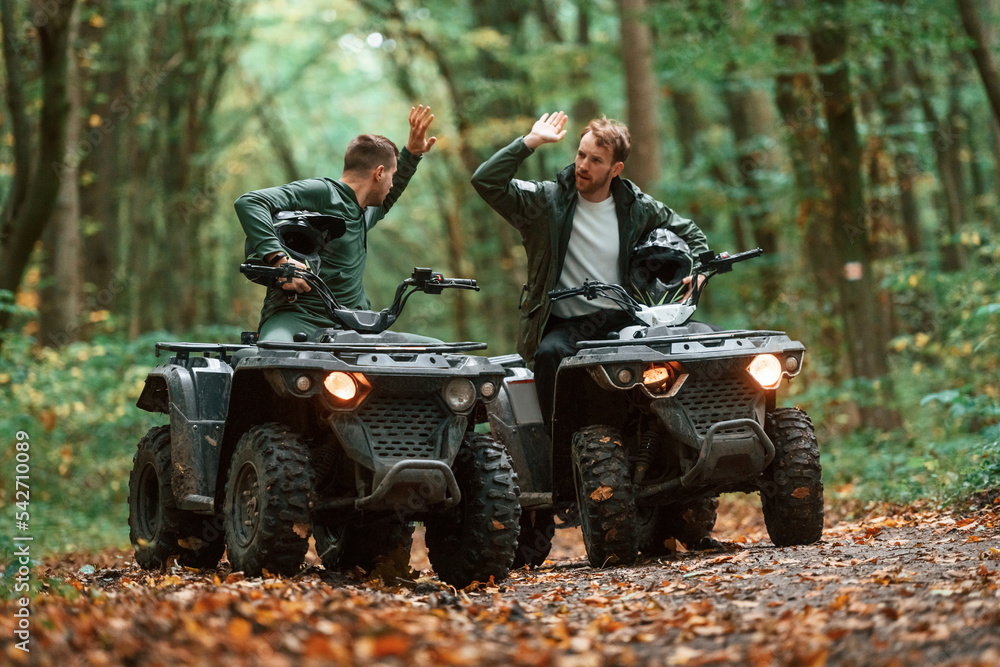 Two male atv riders is in the forest together