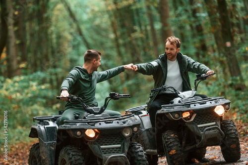 Knocking fists, gesture. Two male atv riders is in the forest together