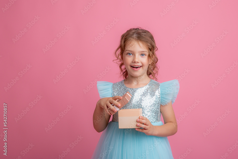 a cute little girl in a beautiful dress holds a fairy's magic wand and a gift on a pink background a cute little girl in a beautiful dress holds a fairy's magic wand and a gift on a pink background