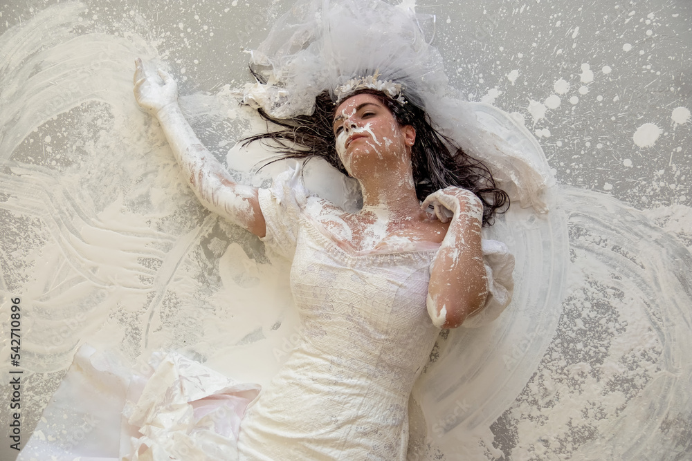 upper body of a beautiful sexy young artistically abstract painted woman,  bride, in wedding dress, covered with white paint, creative, abstract body  art, on the floor in the studio Stock Photo