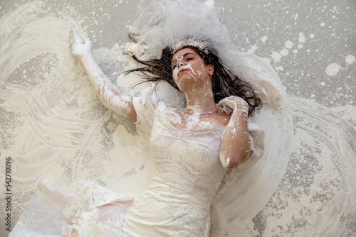 upper body of a beautiful sexy young artistically abstract painted woman, bride, in wedding dress, covered with white paint, creative, abstract body art, on the floor in the studio photo