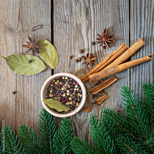Traditional Christmas spices for cooking and drink (mulled wine) on a wooden background with fir branches. Festive atmosphere, copy space.