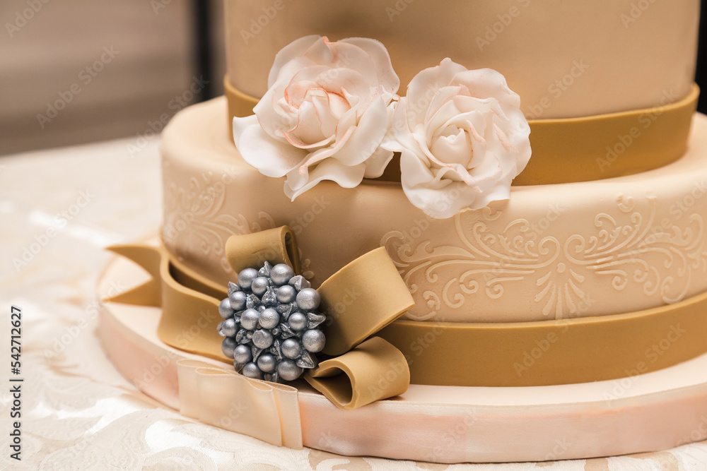 beige wedding cake with roses and ribbons close-up beige wedding cake with roses and ribbons close-up