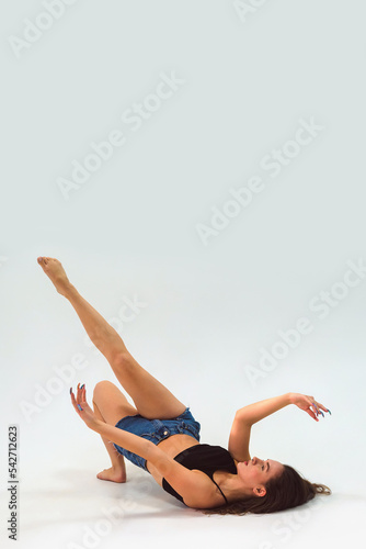 girl dancer lies on the floor and poses. Full length portrait on white background cyclorama