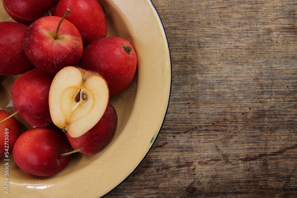Small red Autumn Strawberry shaped Apple cut slice seed in enamel metal plate on rustic wooden background Small red Autumn Strawberry shaped Apple cut slice seed in enamel metal plate on rustic wooden background